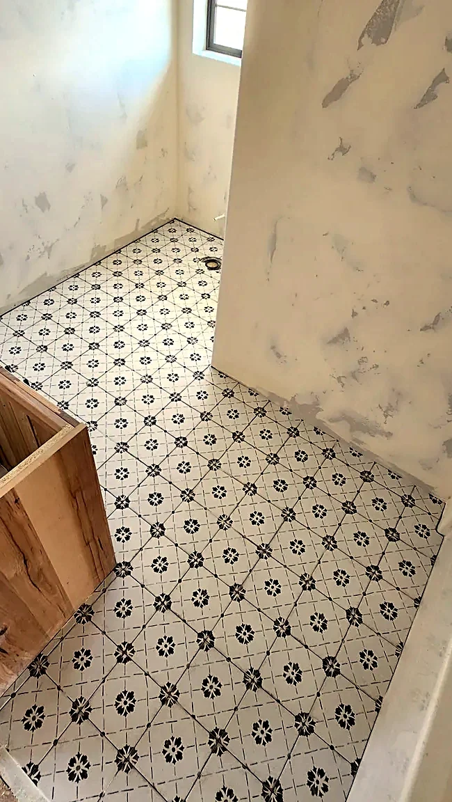 Bathroom floor in cream and black decorative patterned tile, motif registering square across the field