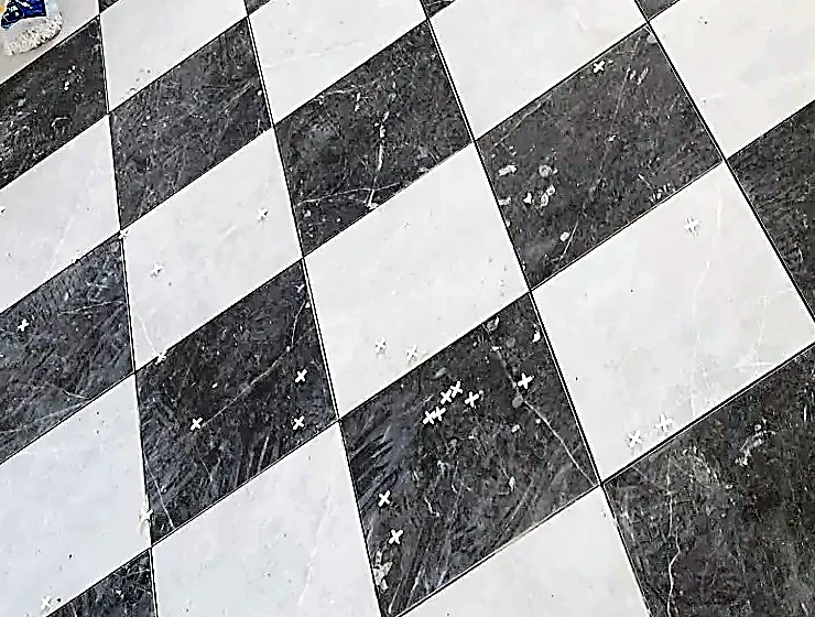 Diagonal marble checkerboard floor, grout width holding across the field