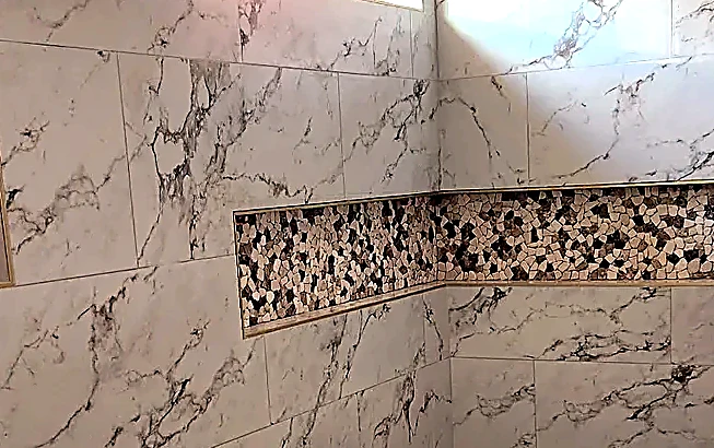 Pebble mosaic accent band running level through the niche