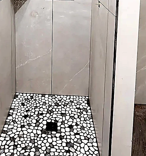 Pebble pan pitched to fall, tile cut close around the drain
