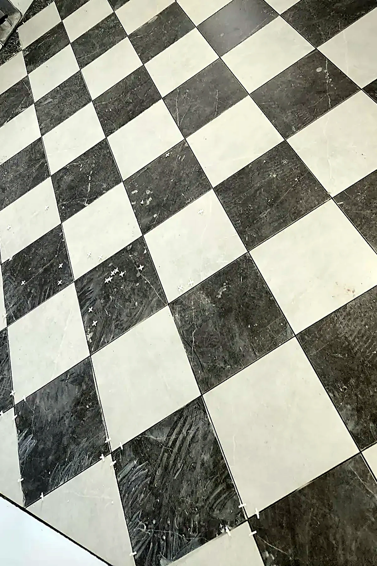 Diagonal black-and-white marble checkerboard floor laid by Prudence Construction, grout lines running true across the full field
